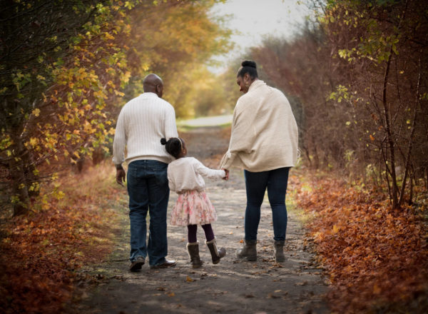 Family walking in autumn woodland during photoshoot in Oxfordshire